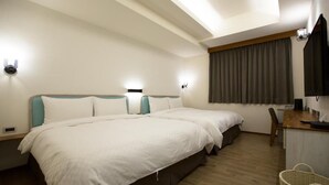 A hotel room with two beds, a desk, a chair, a TV, and a window with curtains. - Yuan Hsiang Hotel (Yuli)