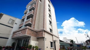A modern hotel with a prominent entrance, multiple floors, and a clear sky. - Yuan Hsiang Hotel (Yuli)