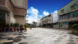 A spacious outdoor area with a checkered pavement, potted plants, and a clear blue sky. - Yuan Hsiang Hotel (Yuli)