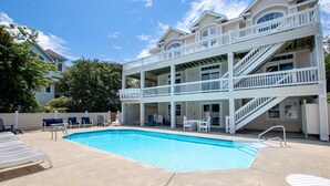 A two-story building with a swimming pool, outdoor seating, and a staircase.