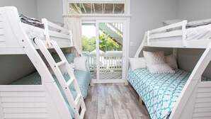 A room with two bunk beds, a balcony, and a view of greenery outside.