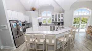A modern kitchen with white cabinets, stainless steel appliances, and a central island with bar stools.