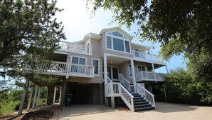 A two-story house with a balcony on the second floor, a covered front porch, and a staircase leading to the entrance.