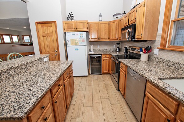 A kitchen with wooden cabinets, granite countertops, a refrigerator, a dishwasher, and a stove.