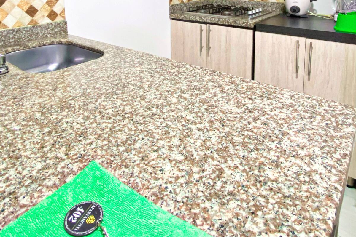 A kitchen with a granite countertop, a sink, a microwave, and a stove.