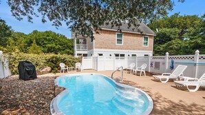 A backyard with a swimming pool, surrounded by a white fence, and a house in the background. - Oceanside, Private Pool, Walking distance to town of Duck, Foosball, T3, Bella Vita (Duck)