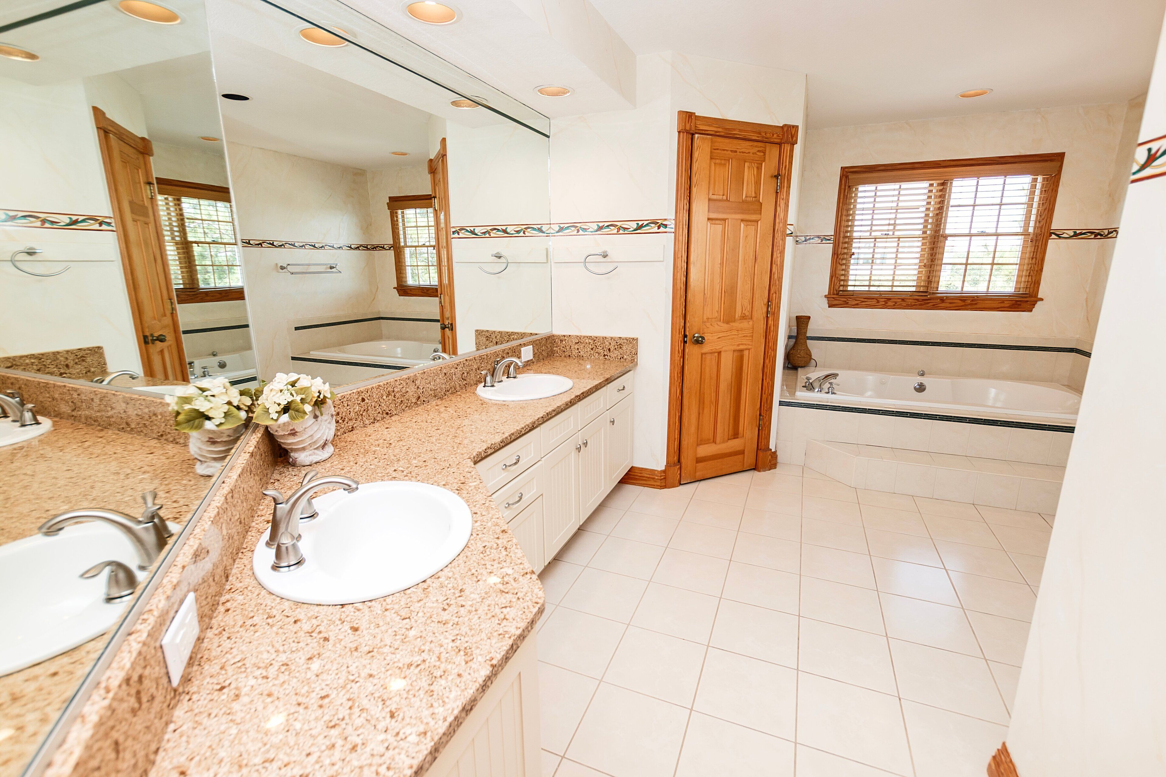 A bathroom with two sinks, a bathtub, and a large mirror.