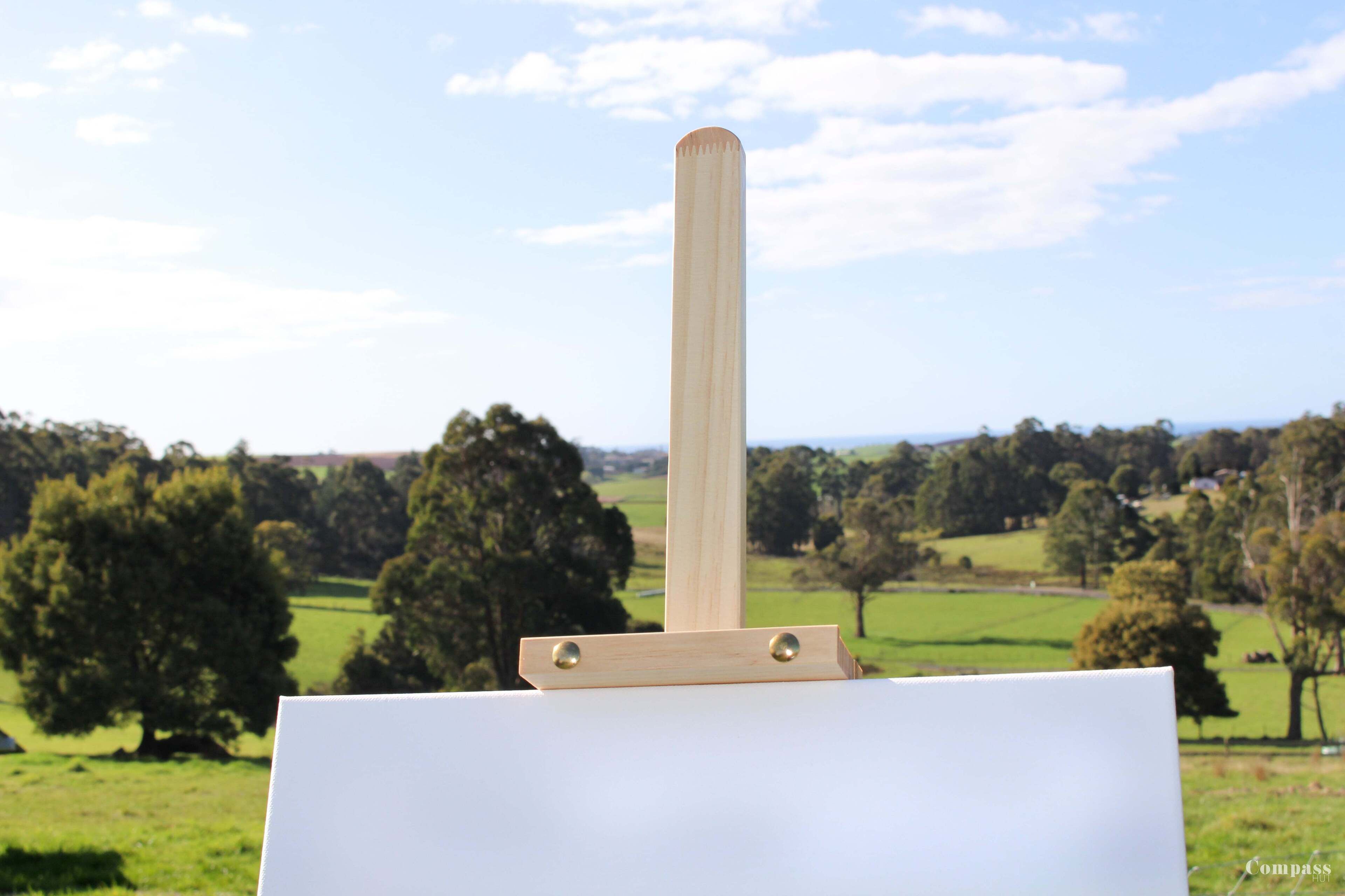 A blank easel with a wooden handle in a landscape setting.