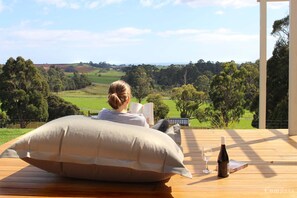 A person sitting on a wooden deck with a view of a green landscape.