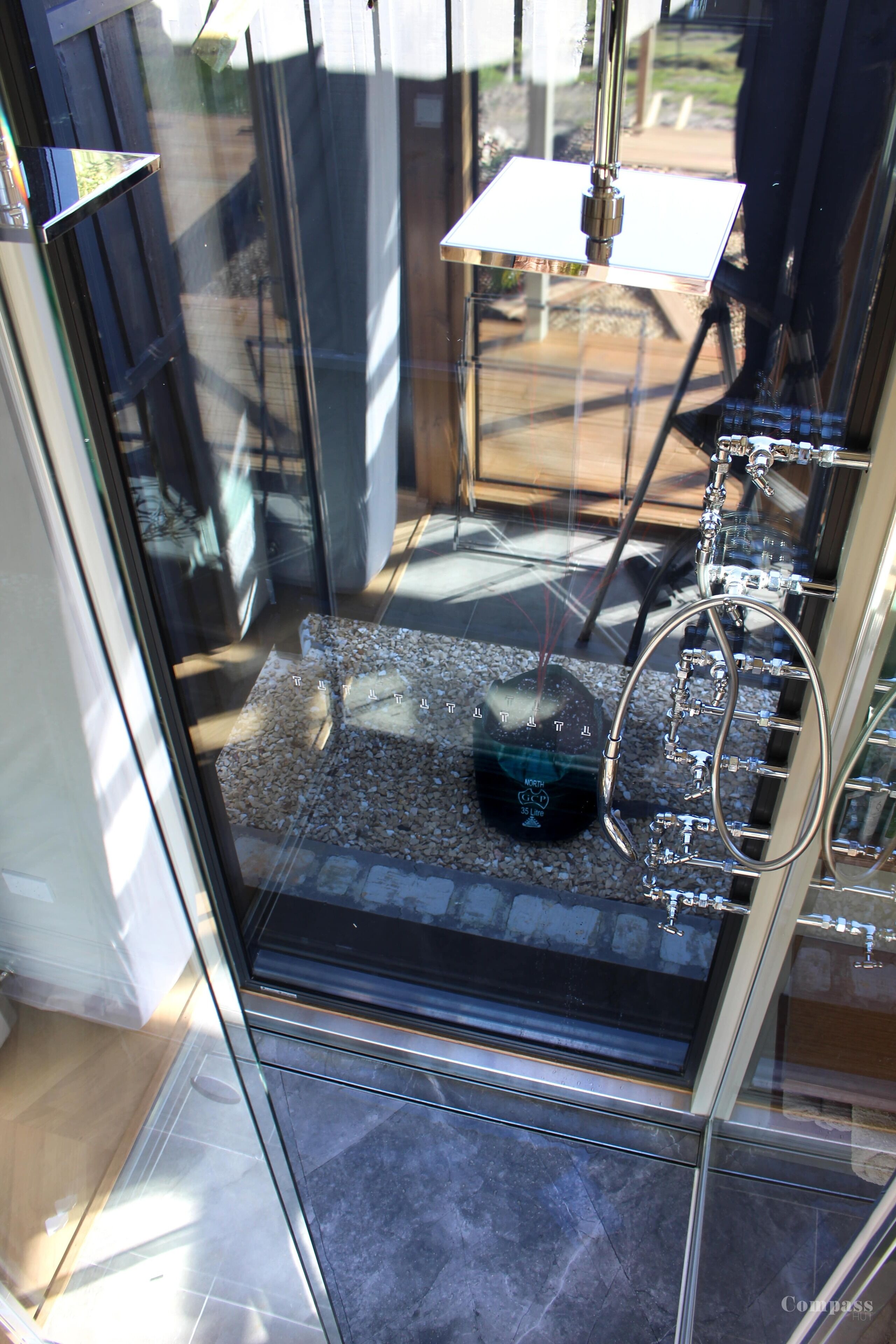 A glass door leading to a room with a small window, a metal rack, and a tiled floor.