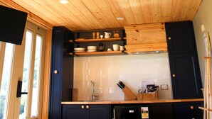 Une cuisine avec des poutres en bois au plafond, un évier, des placards et une fenêtre.