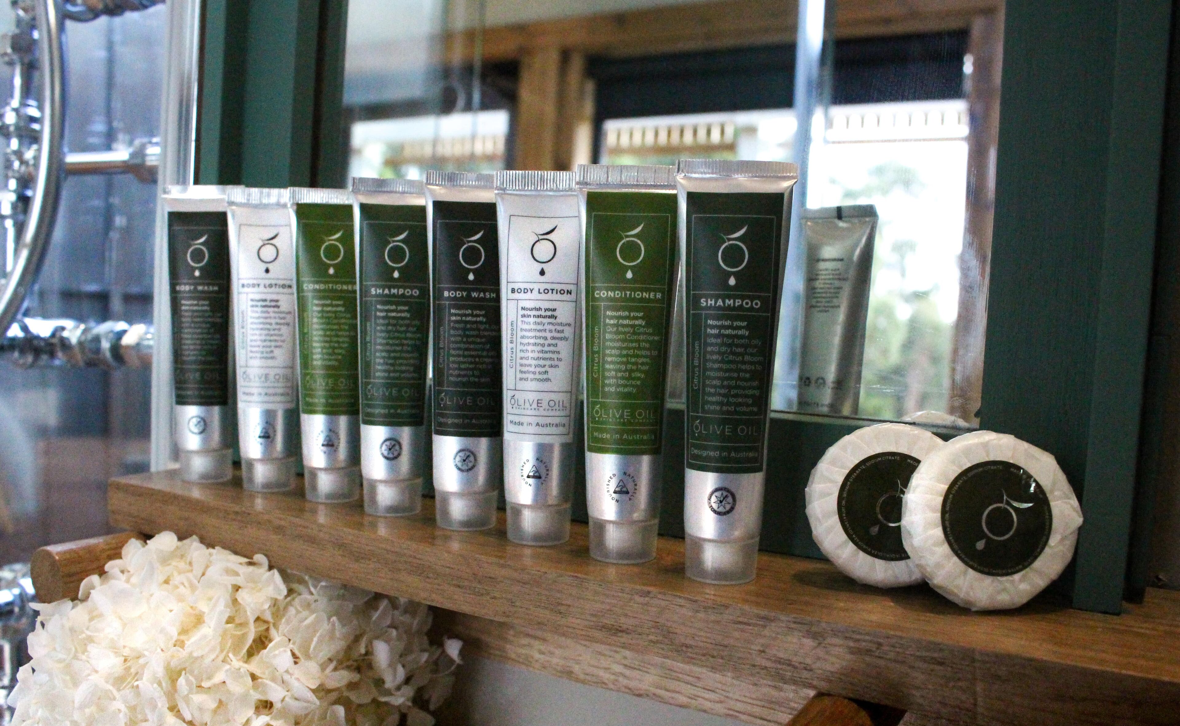 Ein Regal mit verschiedenen Hautpflegeprodukten, darunter Körperlotion, Conditioner und Shampoo, ordentlich angeordnet.