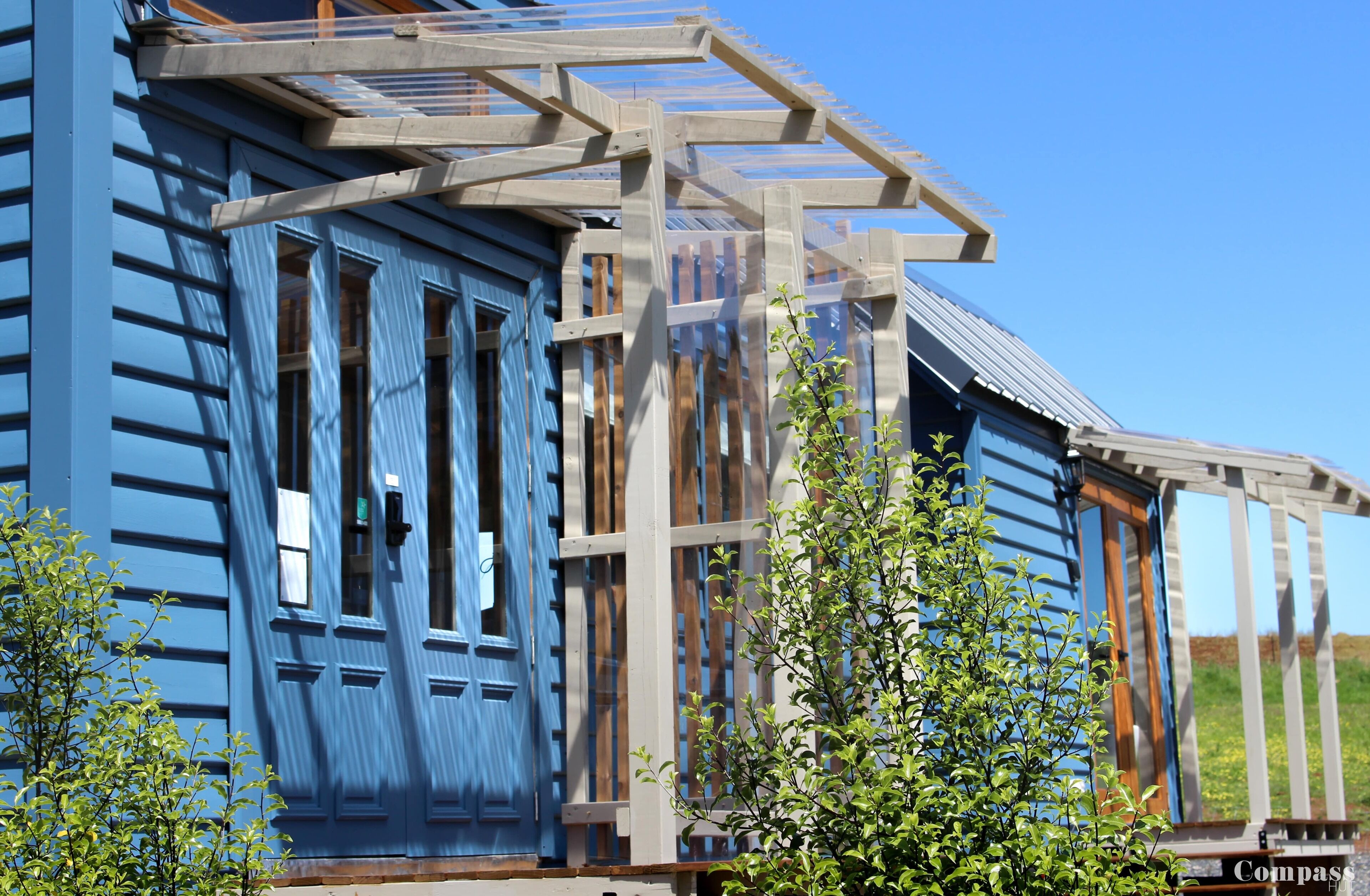 Un edificio de madera azul con un amplio ventanal y un porche de madera.