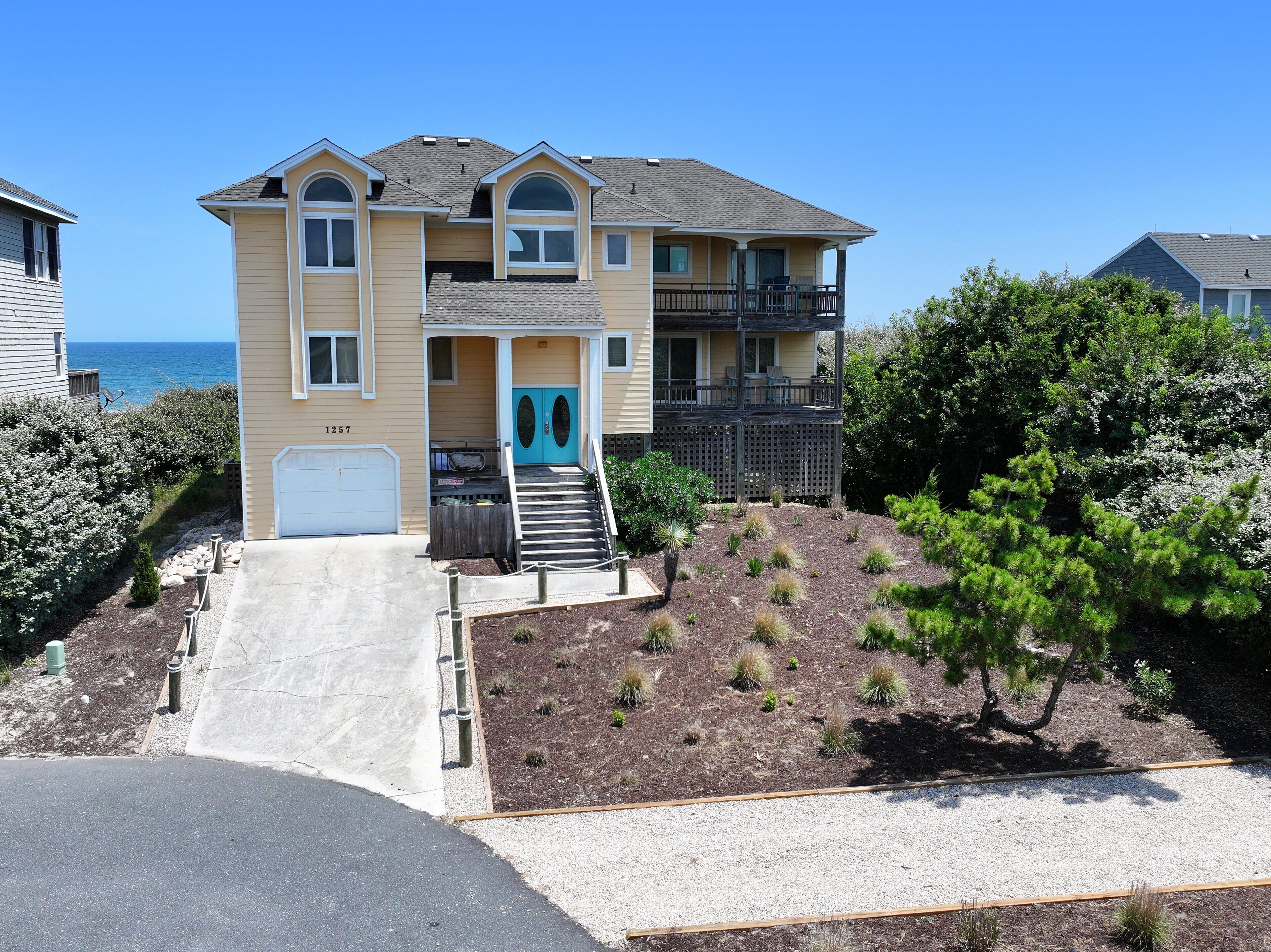 A two-story house with a front porch, a garage, and a view of the ocean.