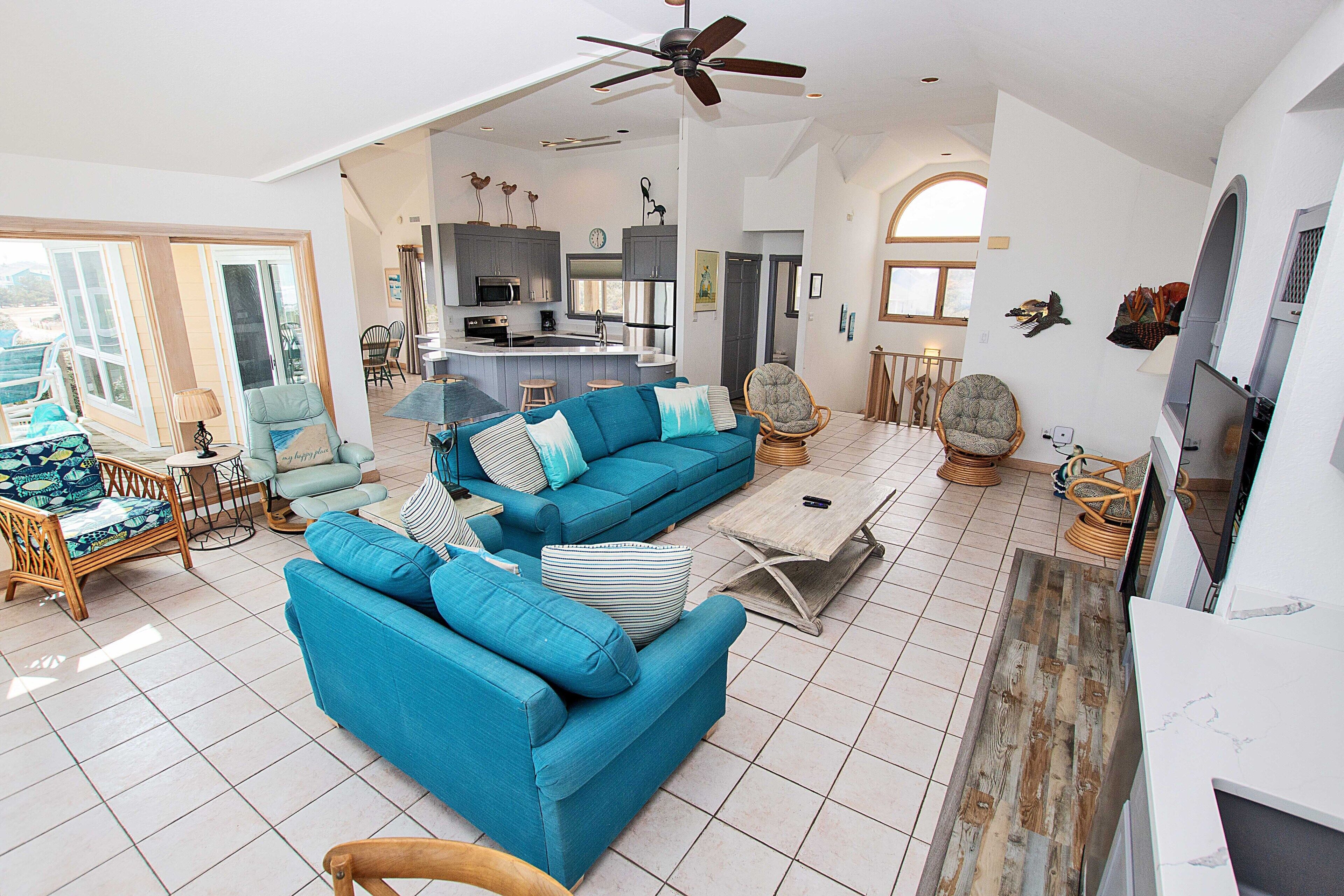 A spacious living area with a blue sofa, a coffee table, and a ceiling fan.