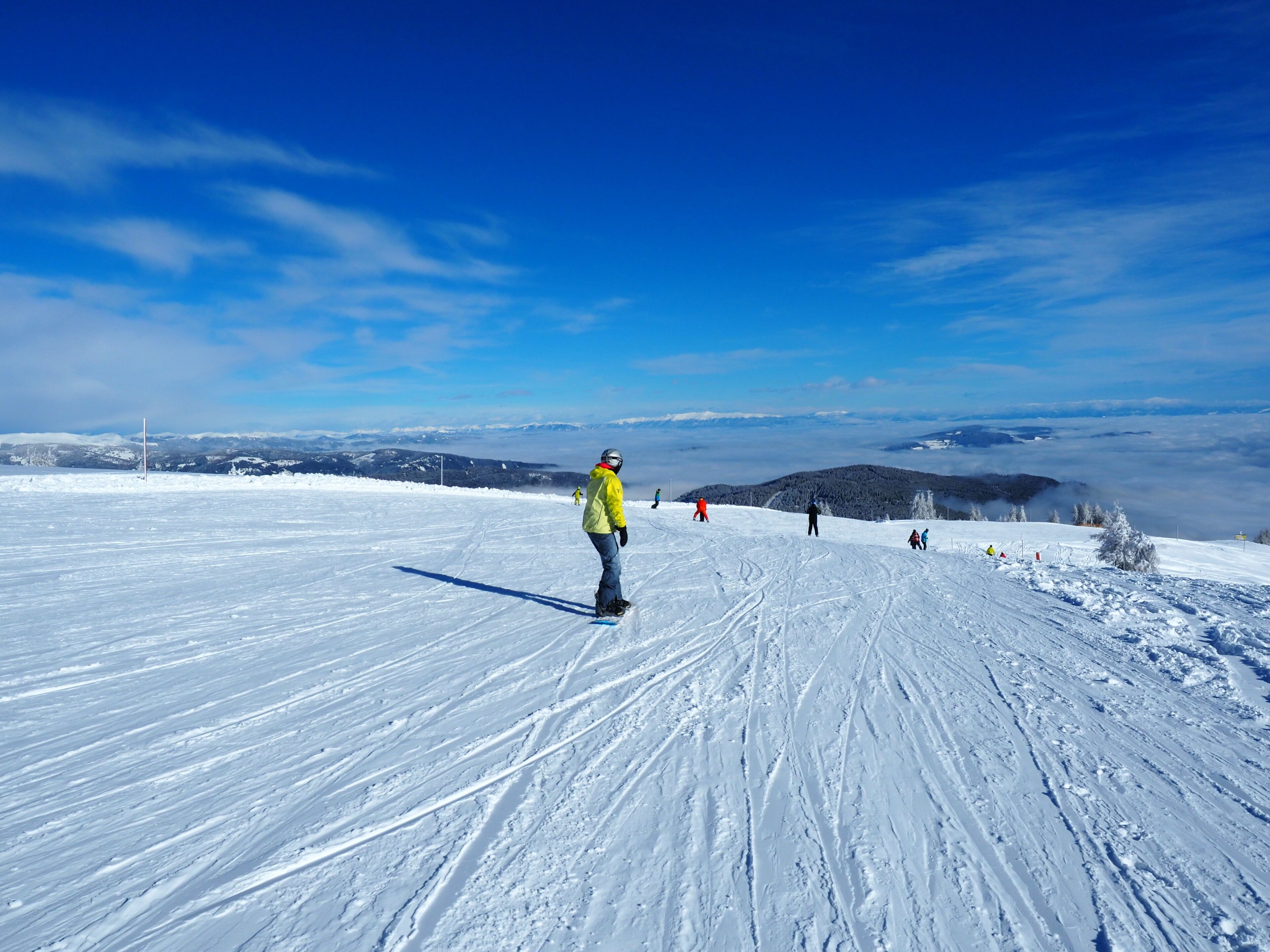 Ein verschneiter Skipisten mit Skifahrern und Snowboardern.