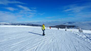 Ein verschneiter Skipisten mit Skifahrern und Snowboardern.