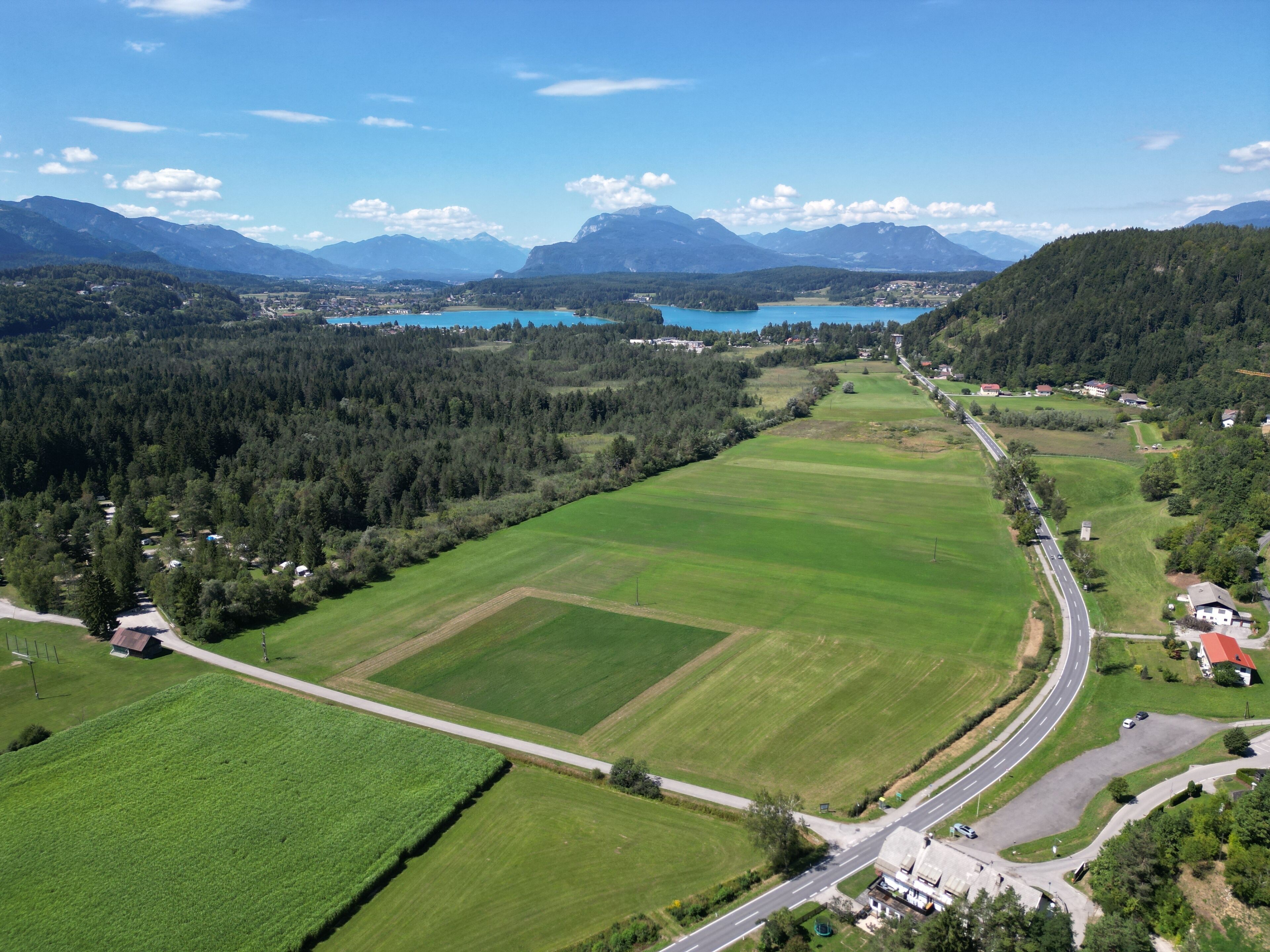 Paesaggio rurale con una strada, campi e un lago.