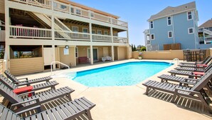 A pool area with lounge chairs and a building with multiple balconies. - Oceanside, 8 BRs, Private Pool and Hot Tub, Pool Table, PI109, Sweet TEA (Corolla)