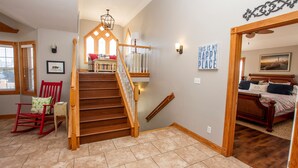 A staircase with wooden railings leading to a bedroom with a bed, a red rocking chair, and a wall sign saying "THIS IS MY HAPPY PLACE". - Oceanside, 8 BRs, Private Pool and Hot Tub, Pool Table, PI109, Sweet TEA (Corolla)