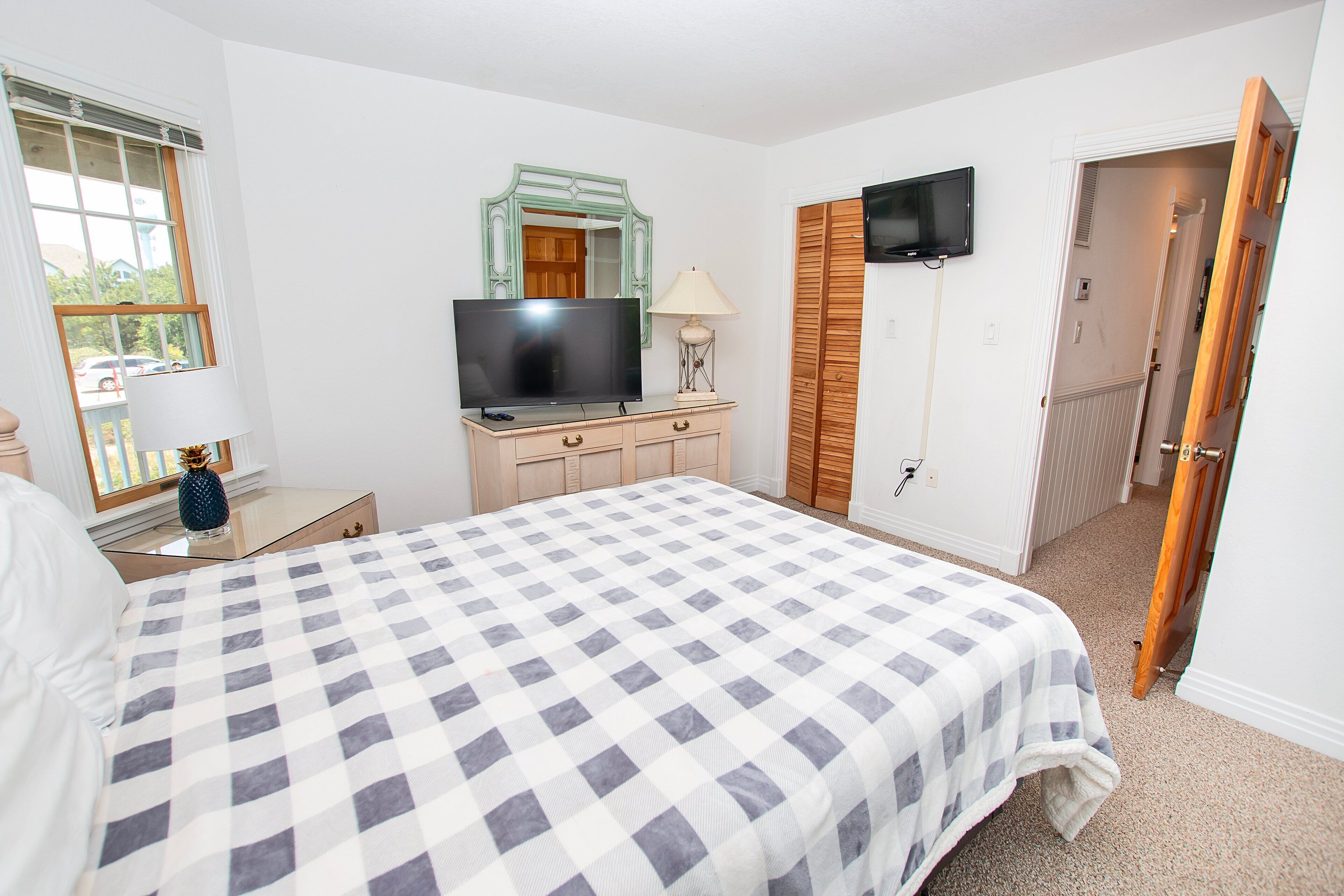 A bedroom with a bed, a dresser, a television, and a mirror.