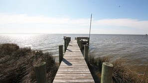 A wooden pier extending into calm water, surrounded by tall grasses.