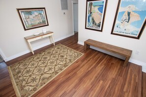 Un couloir avec un banc en bois, une petite table et un tapis à motifs.