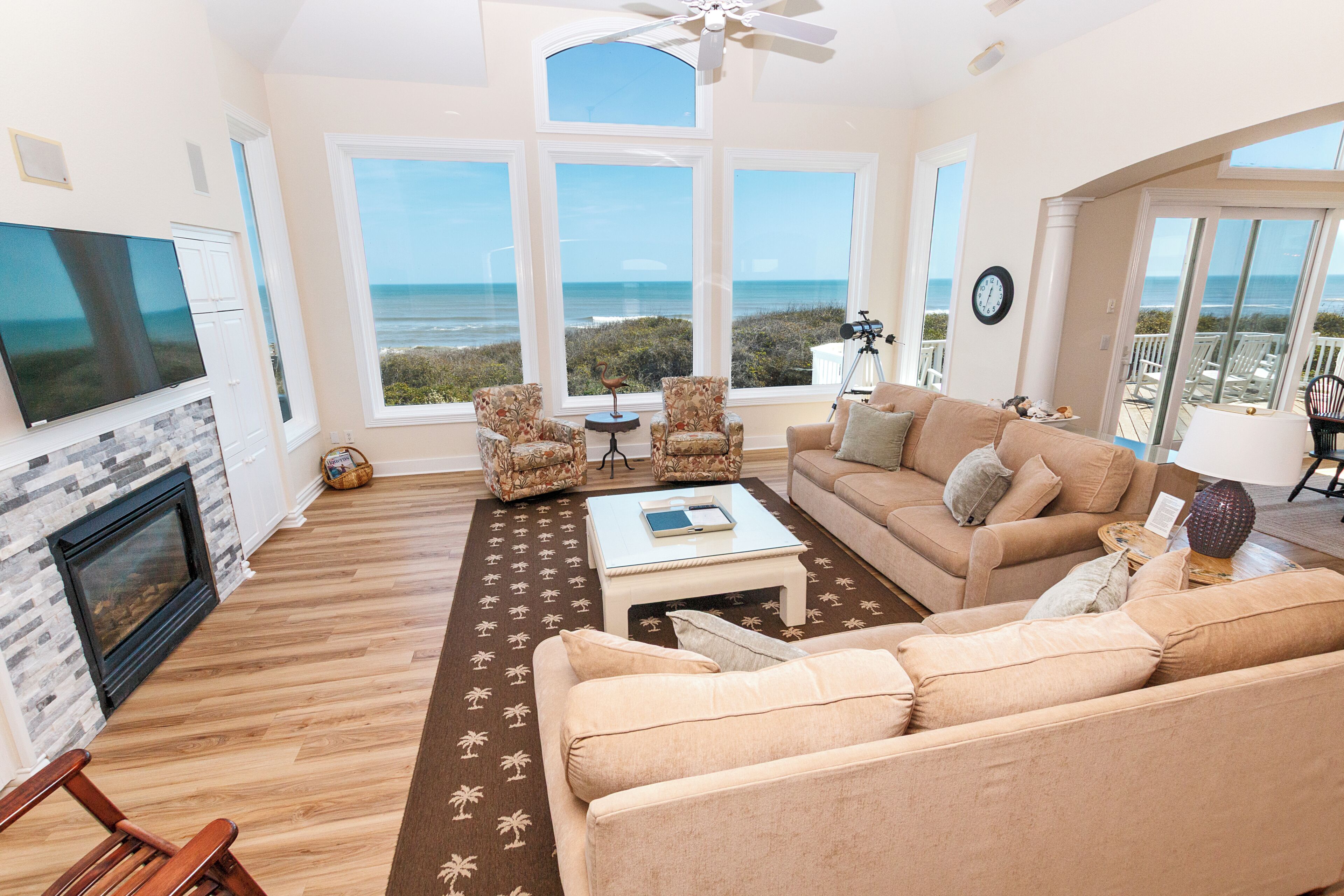 A spacious living room with a large window overlooking the ocean, a fireplace, and a cozy seating area.