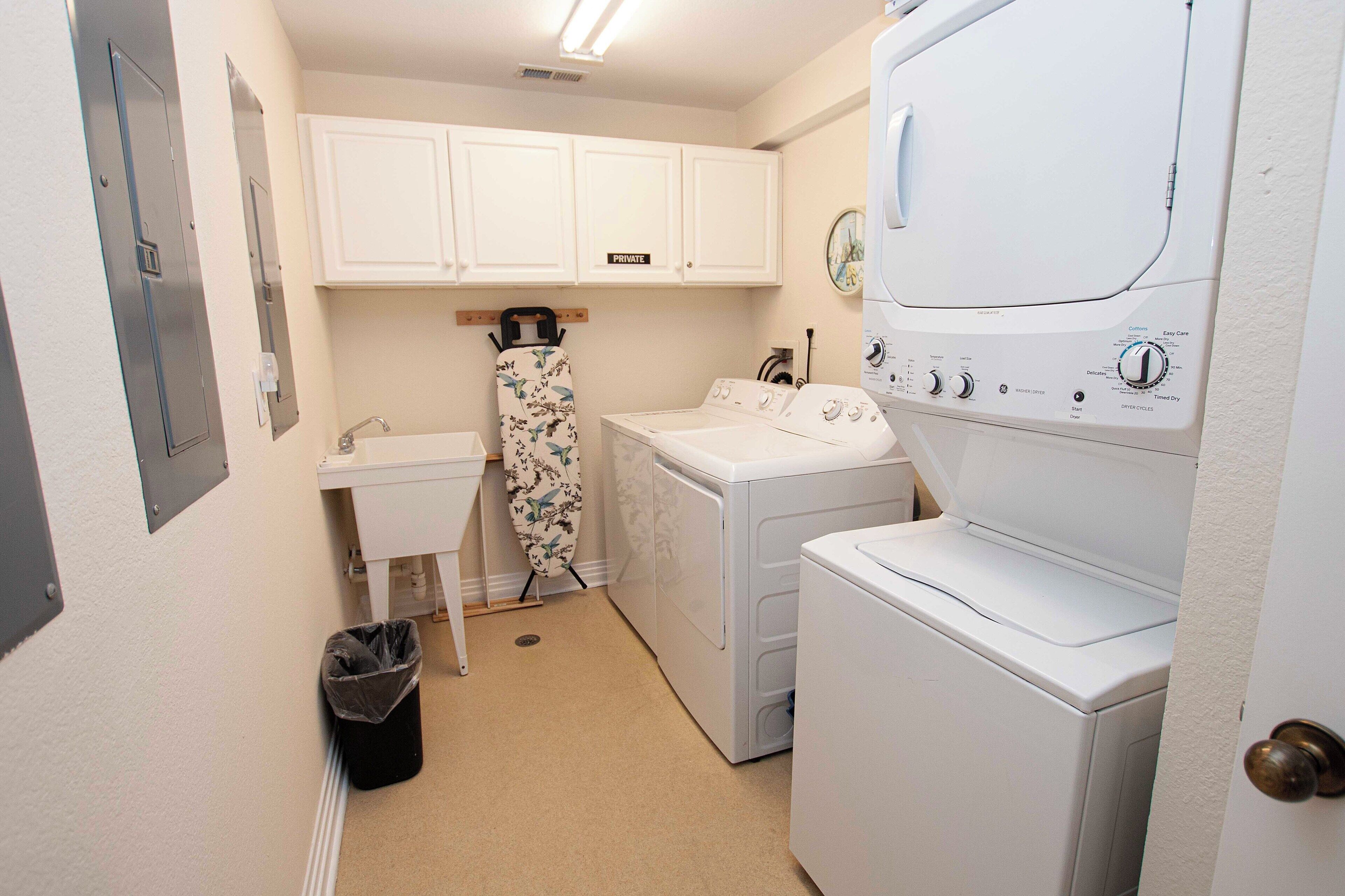 A laundry room with a washing machine, dryer, and ironing board.