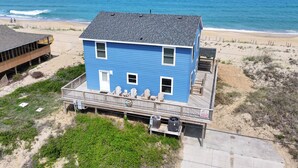 Una casa azul de dos pisos con un balcón, cerca de la playa y con vistas al océano.