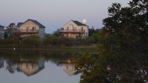 Two houses with balconies overlooking a calm lake, with a full moon in the background. - Oceanside, 7 BRs, Lake Views, Private Pool, Pool Table, Hot Tub, OS1M, Leap of Faith (Corolla)