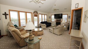 A spacious living room with a sofa, armchairs, a TV, and a fireplace. - Oceanside, 7 BRs, Lake Views, Private Pool, Pool Table, Hot Tub, OS1M, Leap of Faith (Corolla)
