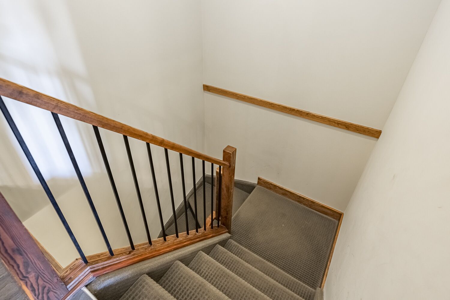 Un escalier avec des rampes en bois et des marches recouvertes de moquette.
