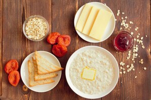 A wooden table with oatmeal, toast, butter, jam, and dried apricots. - Red Fox Hotel in the center (Barnaul)