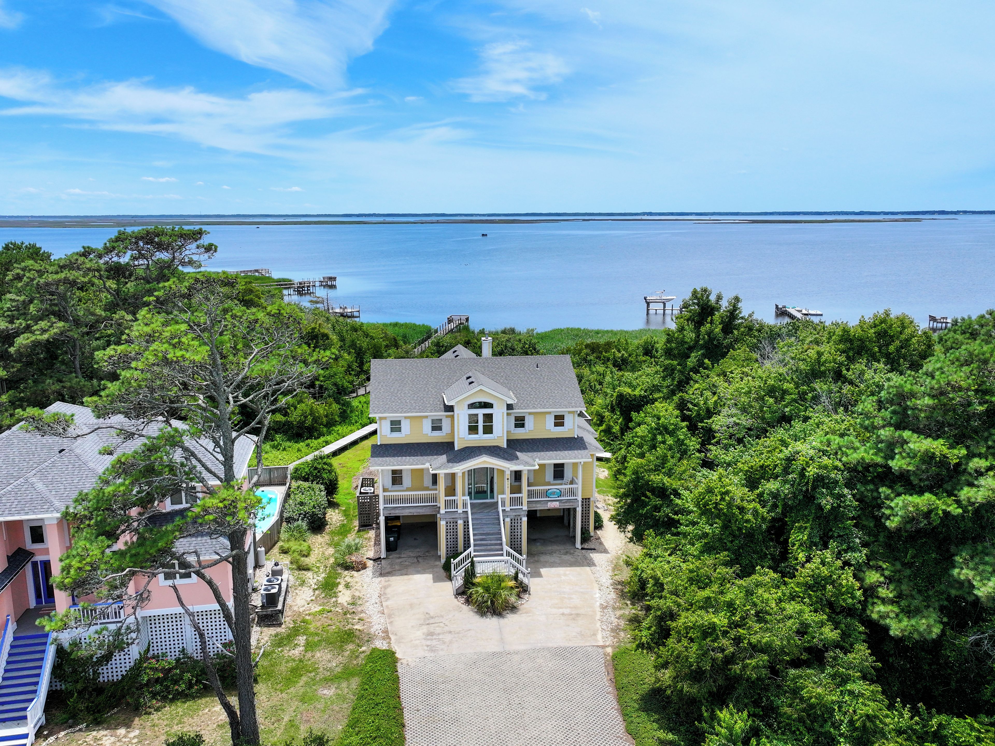 A two-story house with a front porch, a swimming pool, and a view of the water.