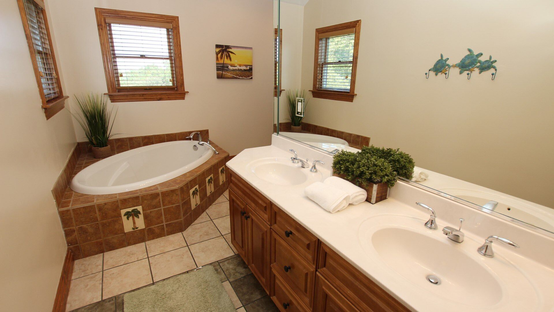 Ein Badezimmer mit einer großen Badewanne, zwei Waschbecken, Holzschränken und dekorativen Wandbildern.