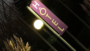 A hotel sign with the name "HOTEL" in large letters, mounted on a pole with a streetlight nearby. - Henri 4 (Rostrenen)