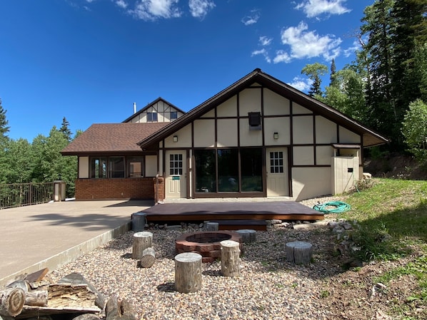 A two-story house with a large front porch, a brick section on the left, and a wooden deck. - 1BD Ski-in/Ski-out Condo Near Lift 8 & 1. Grab a Lift and Ski To Either Lodge. (Brian Head)