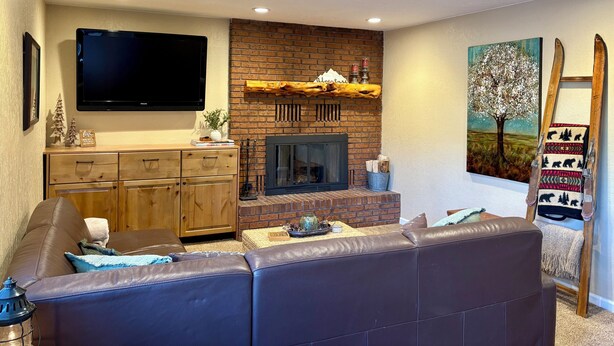 Una sala de estar con chimenea, un televisor de pantalla plana, un sofá y un cuadro.