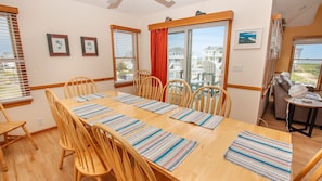 A dining area with a wooden table, striped placemats, and wooden chairs.