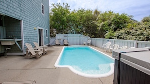 A backyard with a swimming pool, outdoor seating, and a house.