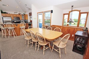 Een keuken met houten kastjes, een roestvrijstalen koelkast en een eethoek met een houten tafel en stoelen.