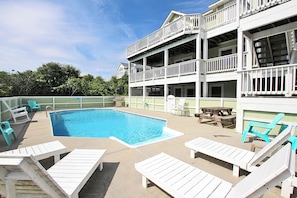 A pool area with lounge chairs, a table, and a building with balconies. - Oceanside, Rec Room, Priv Pool, Hot Tub, Close to Beach Access, PI161, St Nicks (Corolla)