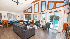 A spacious living area with a sofa, chairs, a dining table, and a balcony with a view.