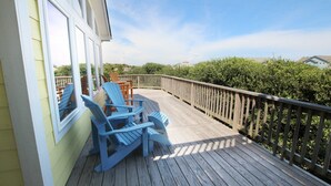 Une terrasse en bois avec des chaises Adirondack bleues et une rambarde en bois.