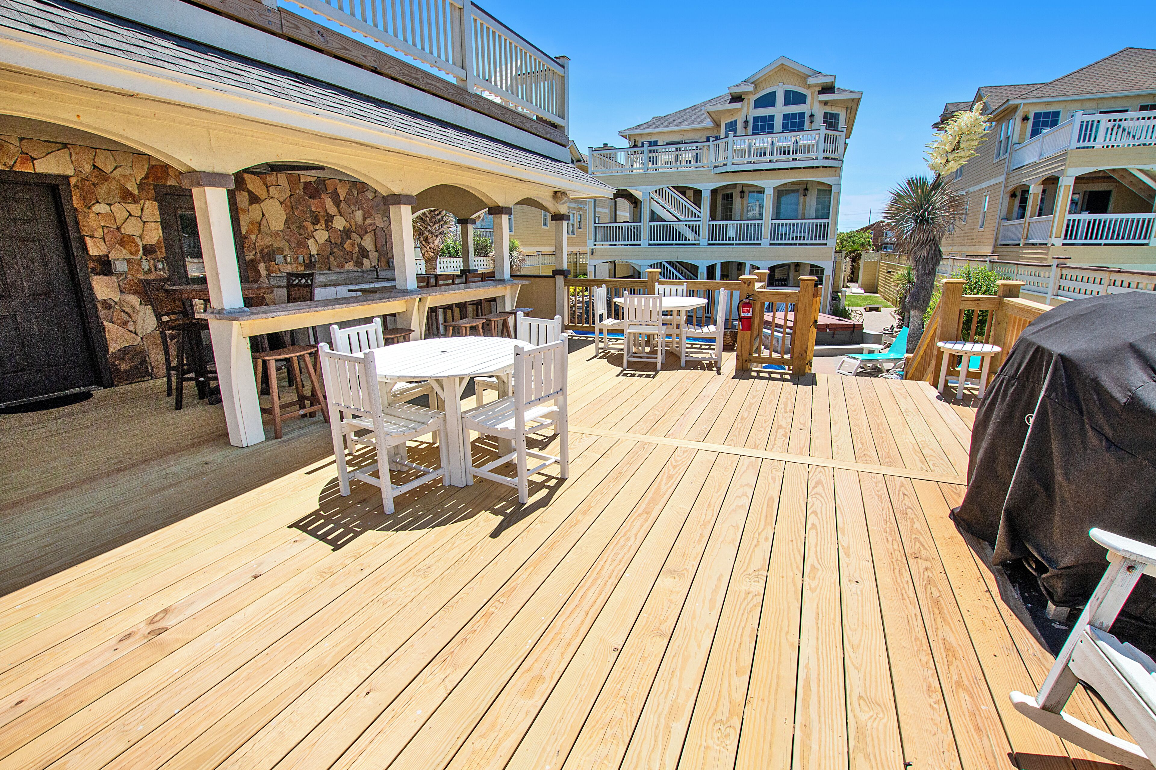 A wooden deck with outdoor seating, a barbecue grill, and a stone wall.