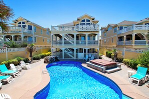 A pool area with lounge chairs, a hot tub, and a multi-story building with balconies. - OCEANFRONT, 11 BRs, Pool, Theater Rm, Elev, Game Rm, KD2, Grand Luxxe (Kill Devil Hills)