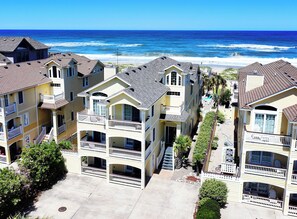 A coastal hotel with multiple balconies, a paved courtyard, and ocean views.