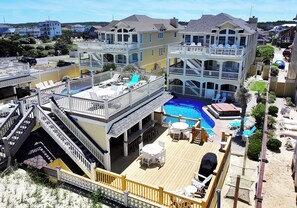 A multi-story hotel with a pool, outdoor seating, and a deck area.