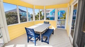 A covered patio with a table and benches, large windows, and a view of neighboring buildings. - Oceanside, Private Pool, Hot Tub, Buck Island Amenities, BU21, Island Girl (Corolla)